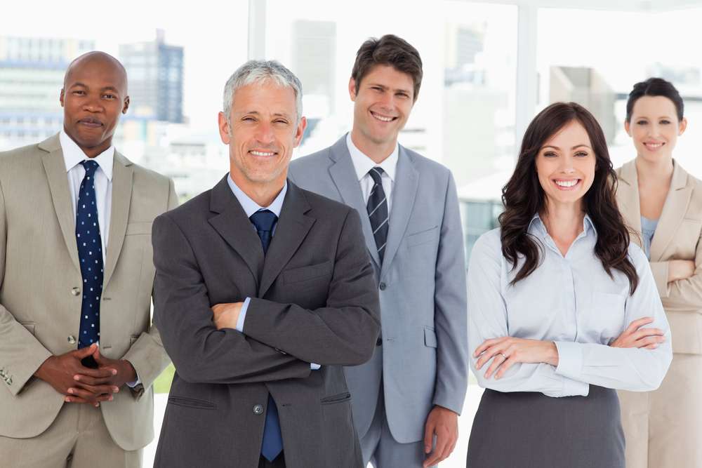 Smiling and confident business team standing in front of a bright window Smiling and confident business team standing in front of a bright window