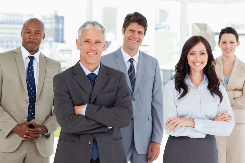 Smiling and confident business team standing in front of a bright window